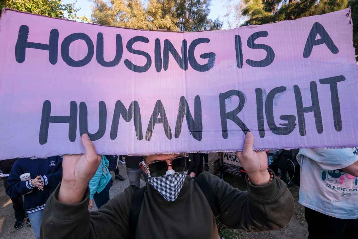 Man hold sign that reads "HOUSING IS A HUMAN RIGHT"