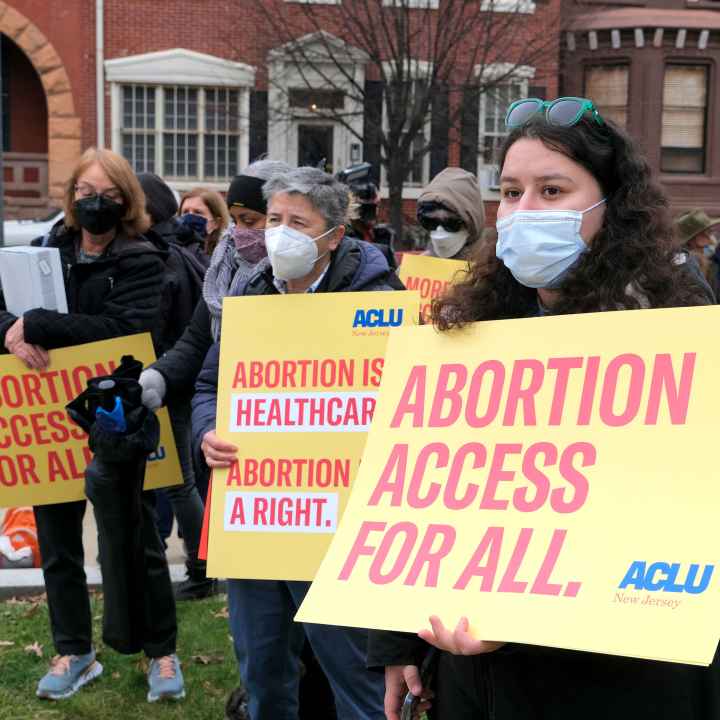 A group of masked protesters are holding signs that read: "Abortion access for all" and "Abortion is healthcare. Abortion is a right."