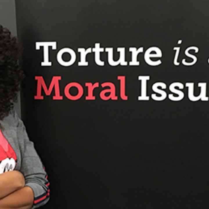 Solitary confinement survivor Nafeesah Goldsmith stands next to the words "torture is a moral issue."