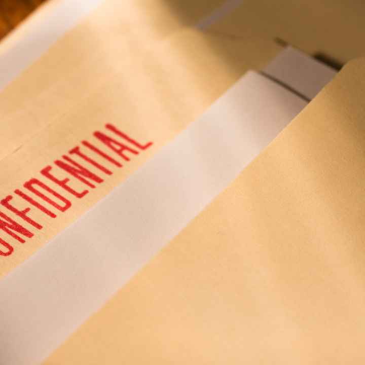 A manila folder with a bright red "confidential" stamp is laid out on a table.