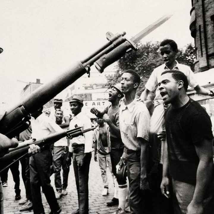 Photograph of Newarkers during the rebellion, who are facing national guard officers holding bayoneted guns.